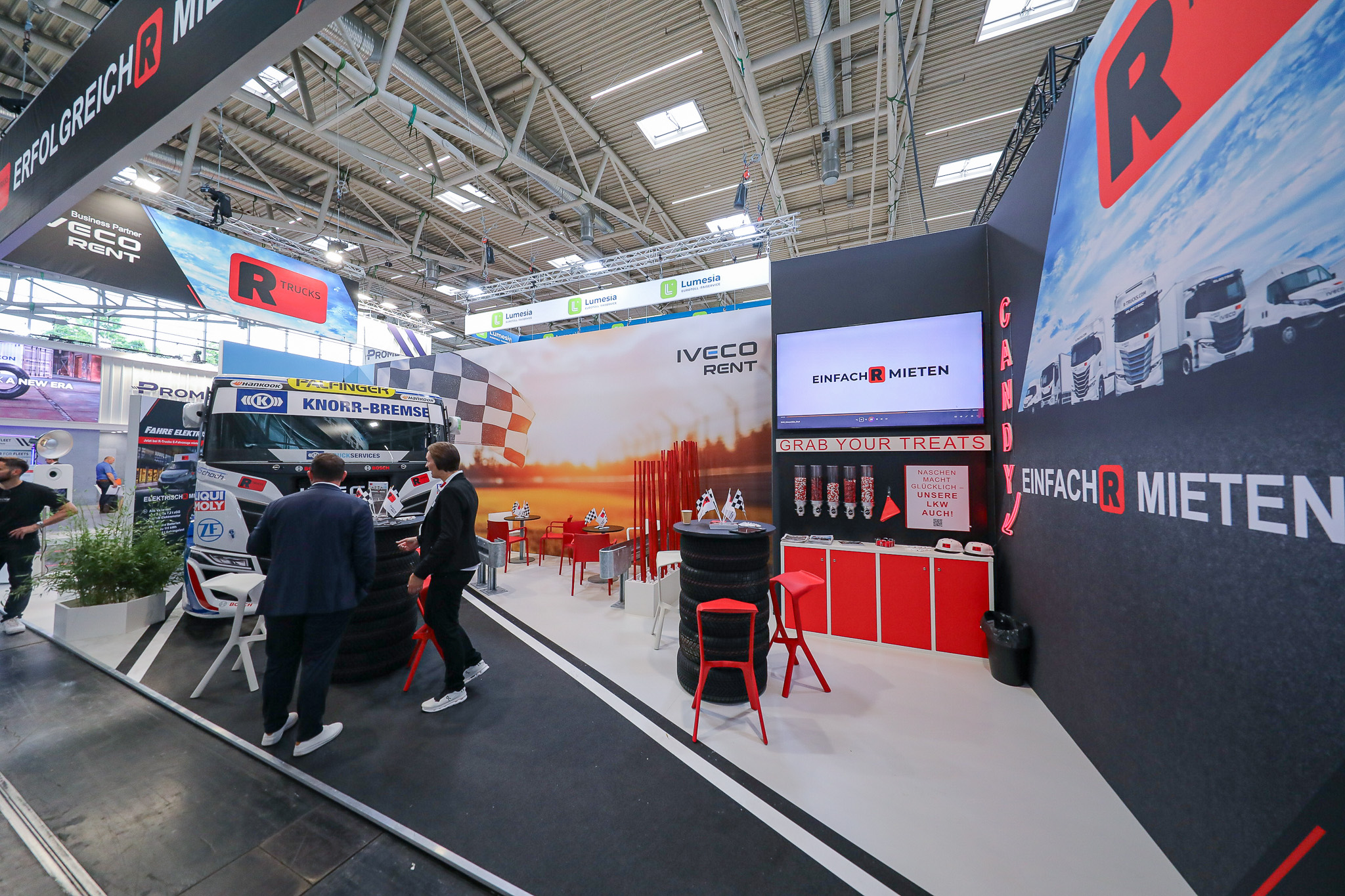 Messestand R-Trucks, zwei Leute und ein LKW stehen darauf
