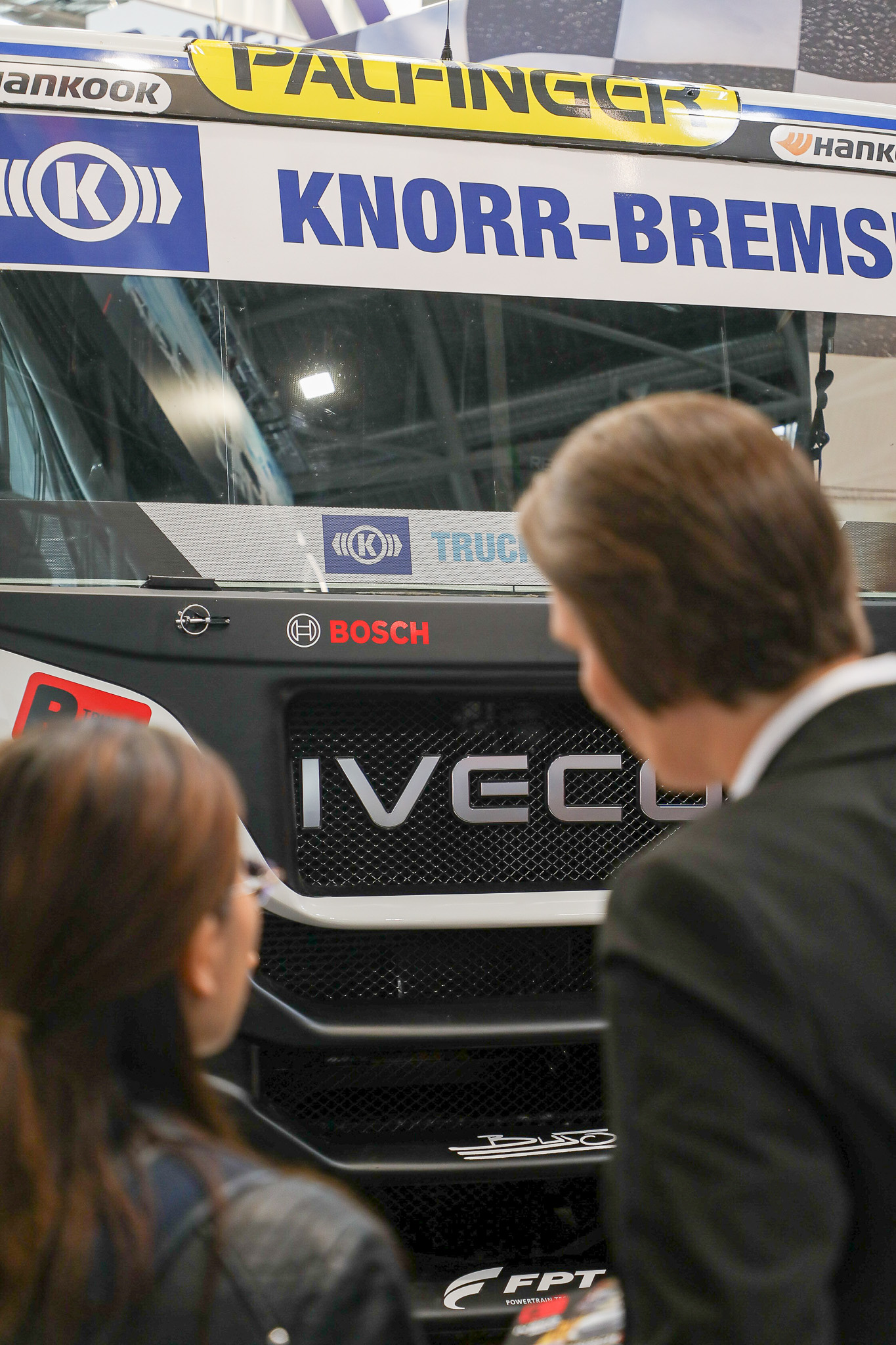 Zwei Personen unterhalten sich vor einem IVECO-LKW im Racing-Livery