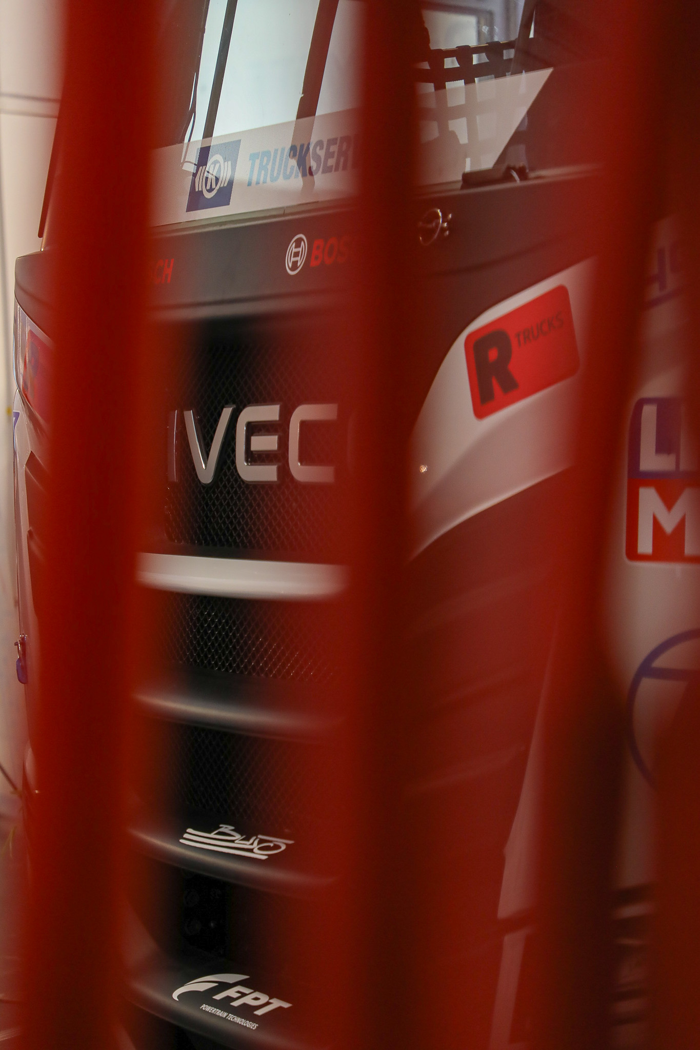 Künstlerischer Close-Up eines LKWs, drei rote Stangen stehen im Vordergrund