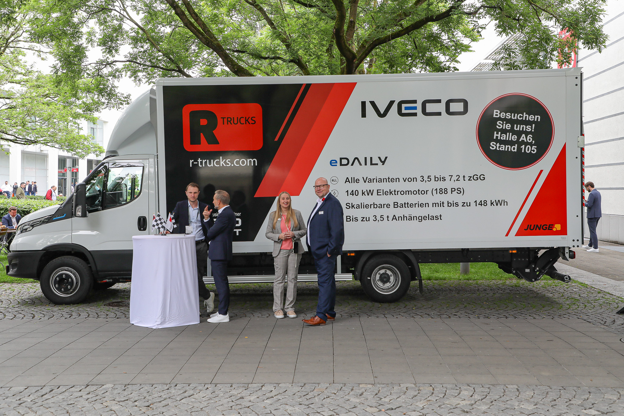 R-Trucks LKW steht draußen, davor ein weißer Tisch, an dem sich mehrere Personen unterhalten