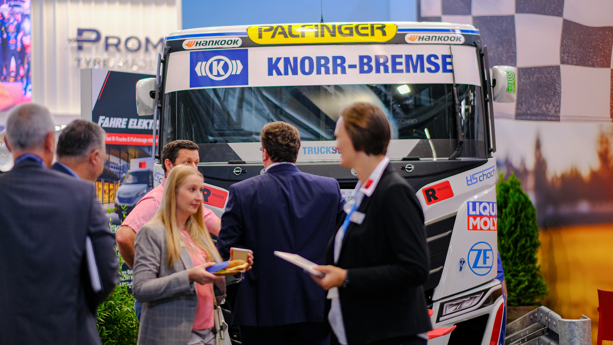 Mehrere Menschen unterhalten sich auf dem Messestand von R-Trucks