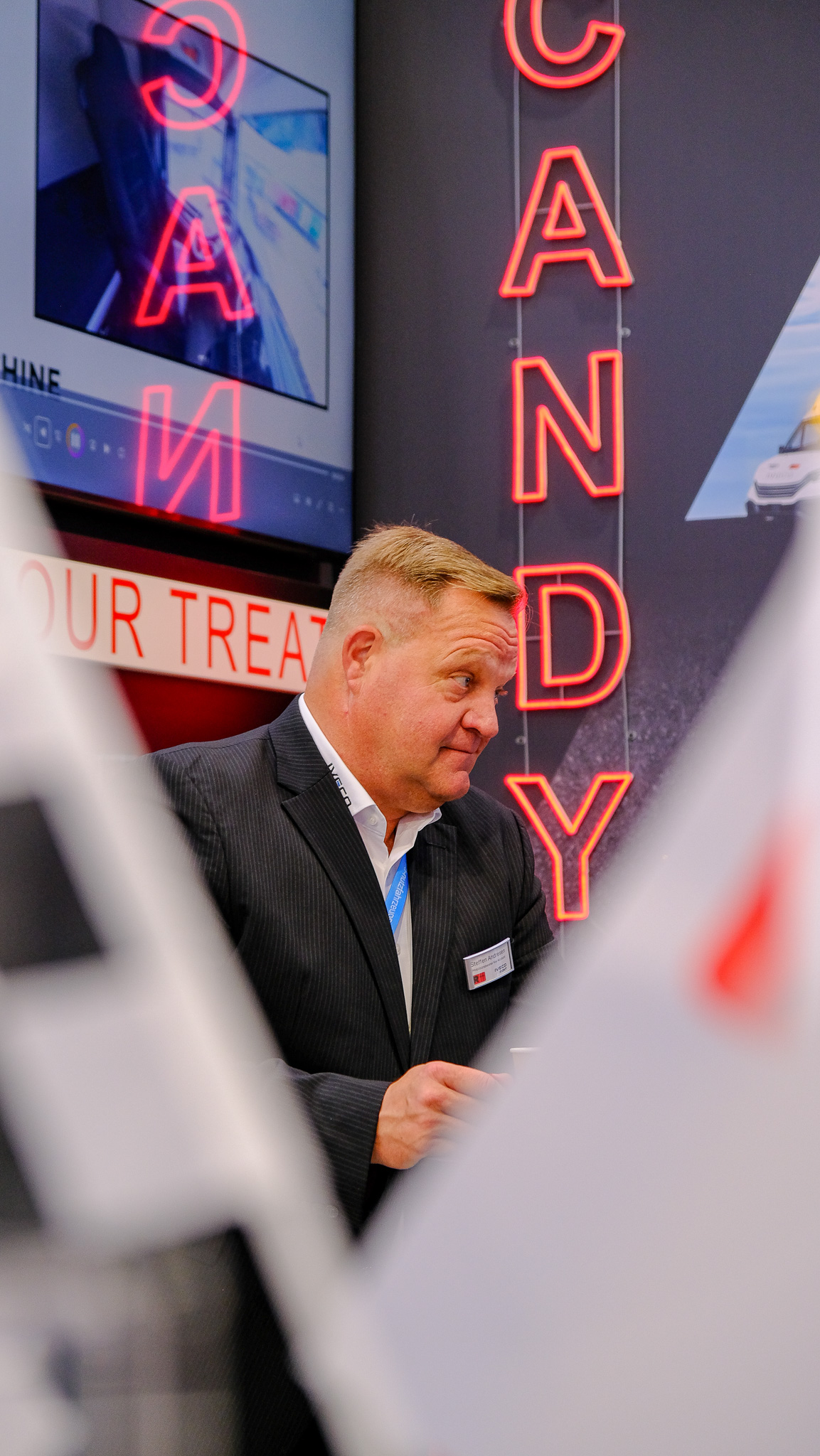 Ein Mann schaut skeptisch in einer Konversation auf dem Messestand von R-Trucks